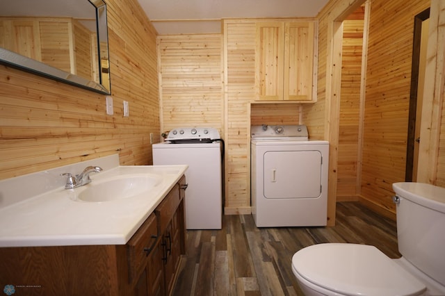 bathroom featuring toilet, washing machine and dryer, and wooden walls