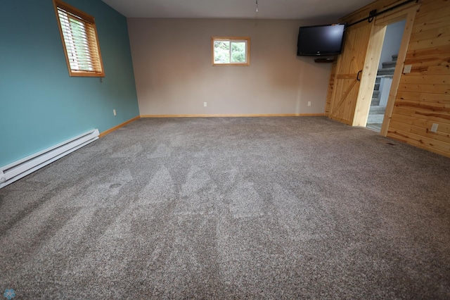 interior space featuring a barn door, a baseboard radiator, wooden walls, and carpet floors