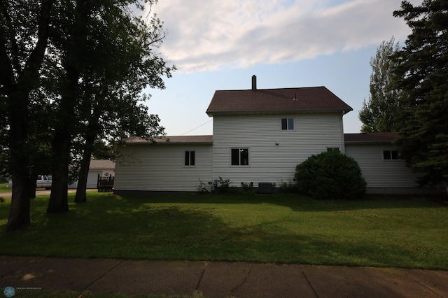 rear view of house featuring a lawn and central AC unit