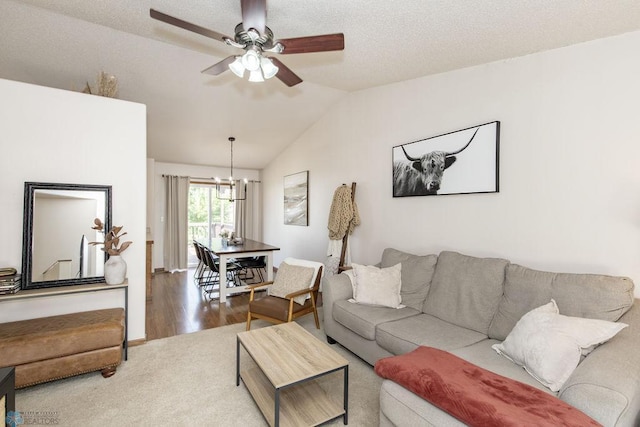 living room featuring lofted ceiling, ceiling fan with notable chandelier, hardwood / wood-style floors, and a textured ceiling