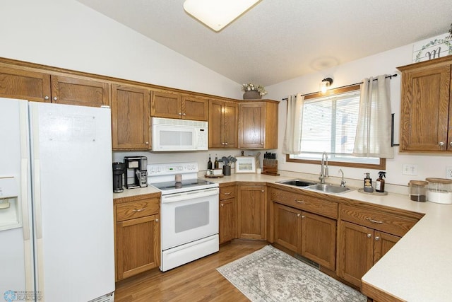 kitchen featuring white appliances, vaulted ceiling, light hardwood / wood-style floors, and sink