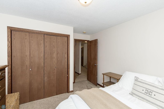 carpeted bedroom featuring a textured ceiling and a closet