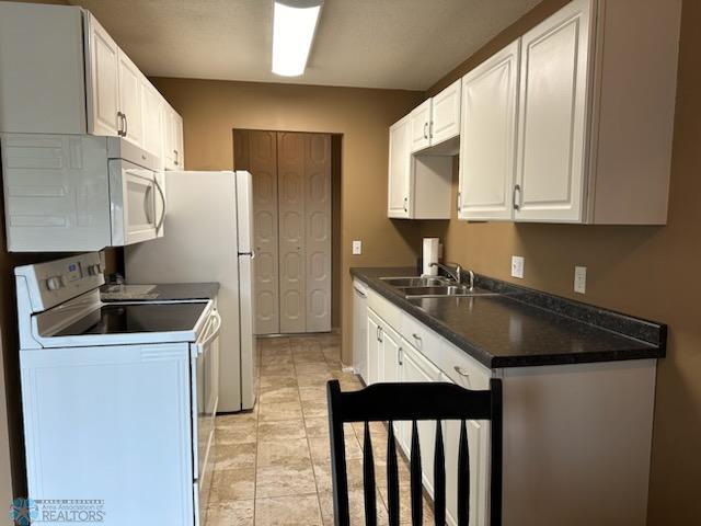 kitchen featuring white cabinets, white appliances, light tile patterned floors, and sink