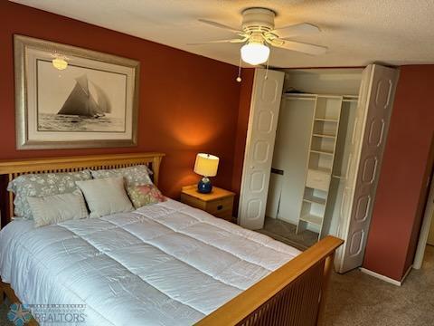 carpeted bedroom featuring ceiling fan and a closet