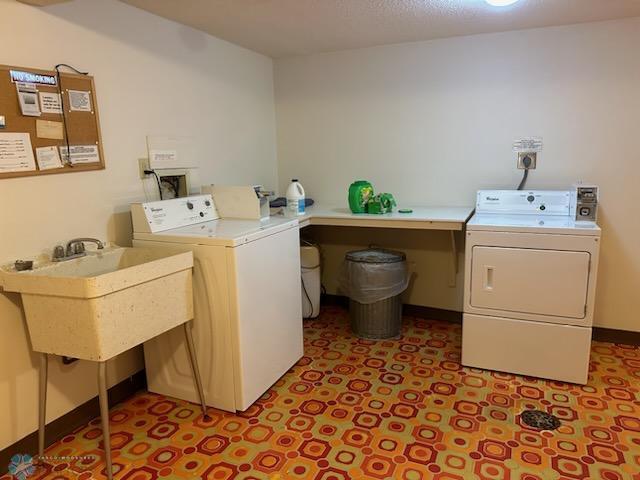 laundry area with tile patterned floors, sink, and separate washer and dryer