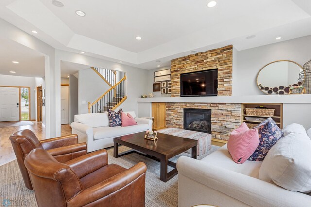 living room featuring a tray ceiling, a fireplace, and light hardwood / wood-style floors