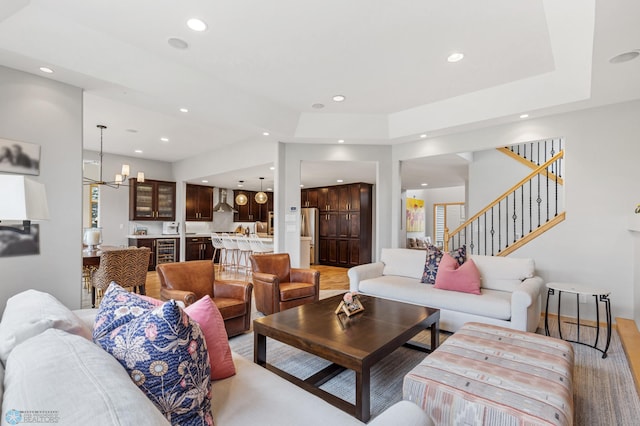 living room featuring wine cooler, a notable chandelier, and wood-type flooring