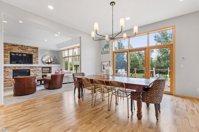 dining area with light hardwood / wood-style flooring, a notable chandelier, and a fireplace