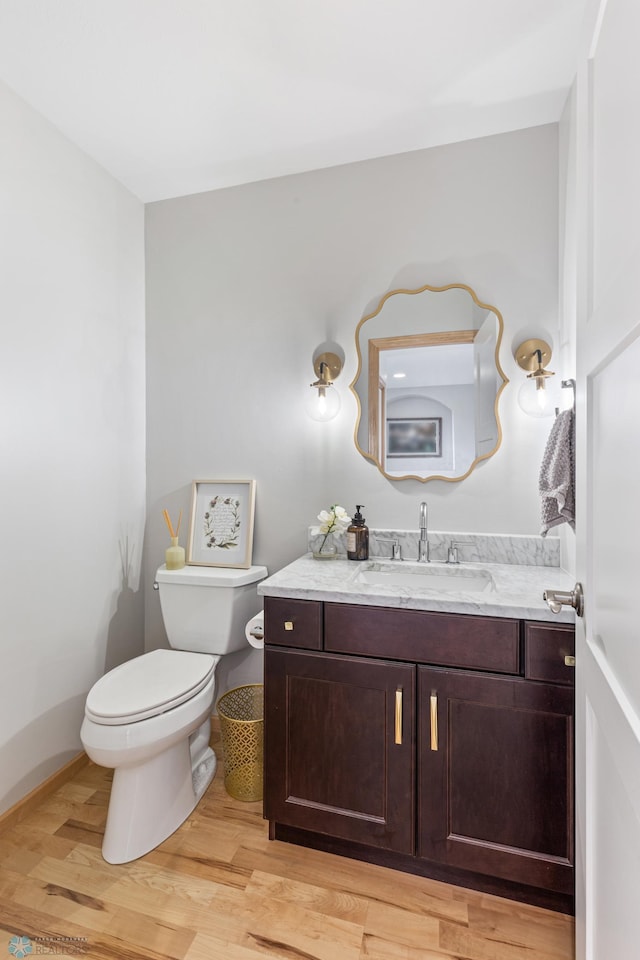 bathroom with toilet, hardwood / wood-style floors, and vanity