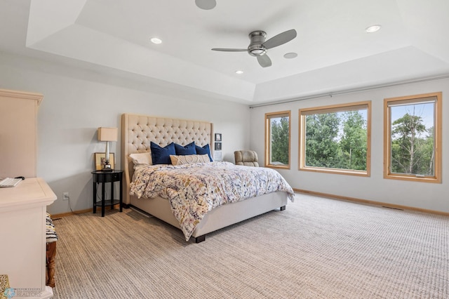 carpeted bedroom featuring a raised ceiling and ceiling fan