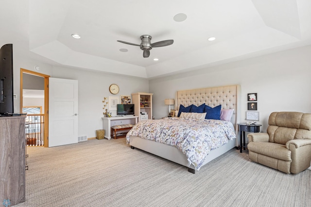 bedroom featuring ceiling fan, a tray ceiling, and light colored carpet