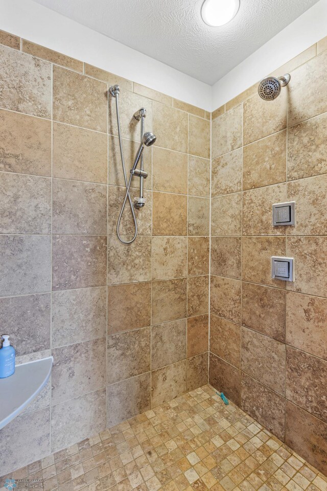 bathroom with a textured ceiling and tiled shower