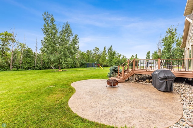 exterior space with a wooden deck, a patio, an outdoor fire pit, and a playground