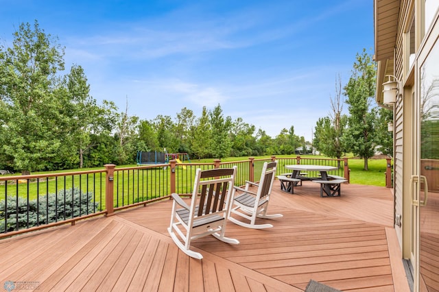 deck featuring a playground, a yard, and a trampoline