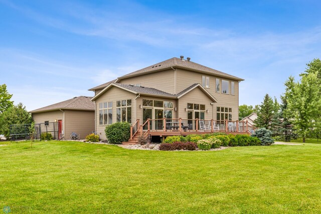 rear view of property featuring a wooden deck and a lawn