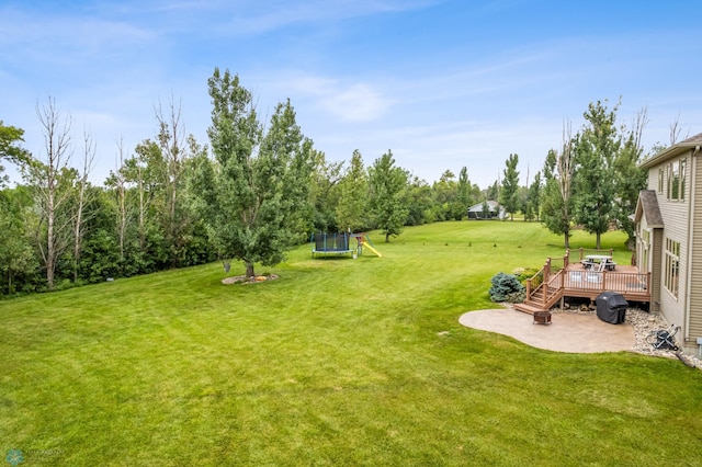 view of yard with a playground, a deck, and a trampoline