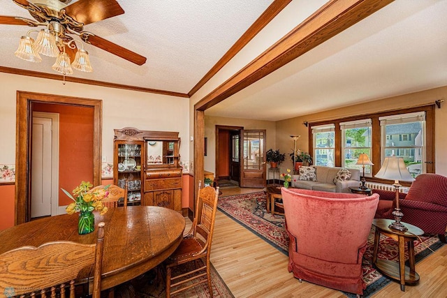 dining area with light wood-type flooring, crown molding, a textured ceiling, and ceiling fan