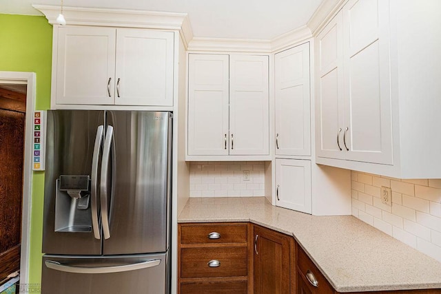 kitchen featuring pendant lighting, light stone counters, decorative backsplash, stainless steel fridge with ice dispenser, and white cabinets