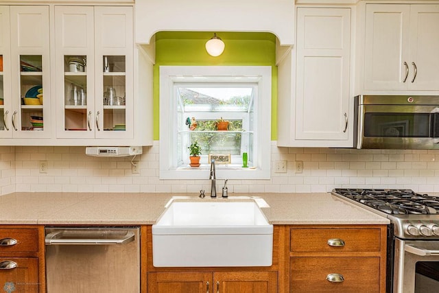 kitchen with appliances with stainless steel finishes, decorative backsplash, light stone countertops, and sink