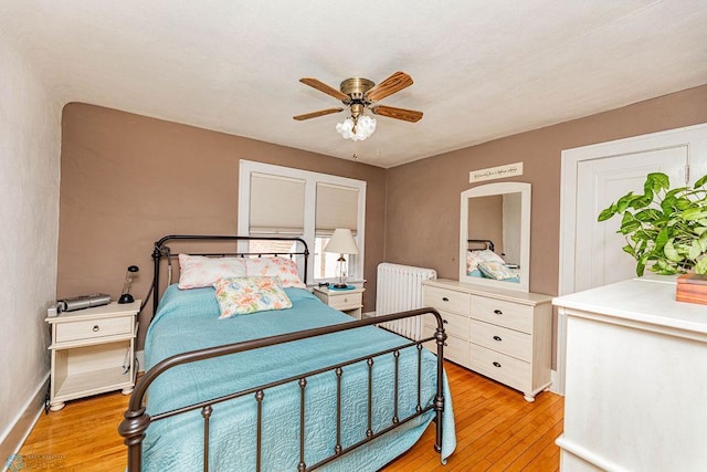 bedroom with ceiling fan, light hardwood / wood-style floors, and radiator heating unit