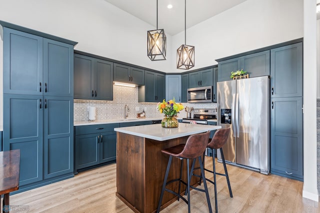 kitchen featuring a kitchen bar, a center island, stainless steel appliances, high vaulted ceiling, and light wood-type flooring