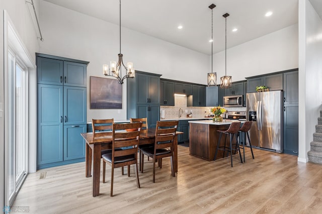 kitchen featuring a kitchen island, stainless steel appliances, decorative light fixtures, and light hardwood / wood-style floors