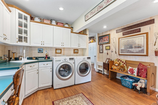 laundry room featuring light wood-type flooring, sink, cabinets, and washing machine and dryer