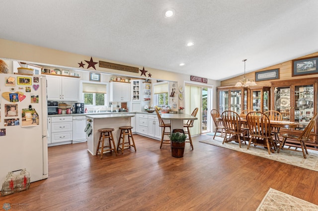 kitchen featuring vaulted ceiling, plenty of natural light, a kitchen bar, and white fridge