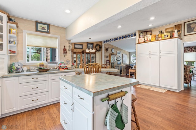 kitchen with white cabinetry, a textured ceiling, light hardwood / wood-style flooring, and a kitchen island