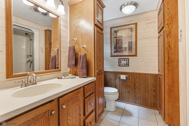 bathroom with a textured ceiling, tile patterned floors, toilet, wood walls, and vanity