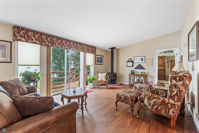 living room featuring vaulted ceiling, a textured ceiling, hardwood / wood-style flooring, and a wood stove