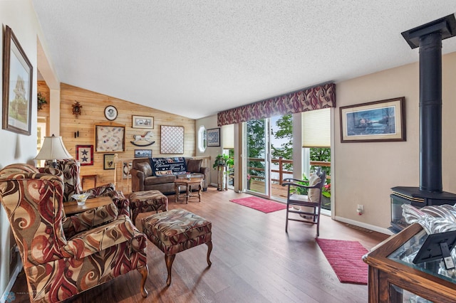 living room with lofted ceiling, wood walls, hardwood / wood-style floors, and a textured ceiling