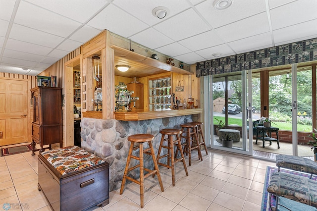 bar with light tile patterned floors, french doors, and a drop ceiling