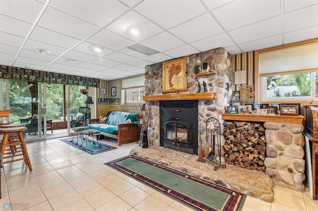 tiled living room with a stone fireplace and a drop ceiling