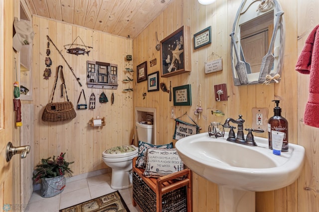 bathroom featuring wood walls, wood ceiling, toilet, sink, and tile patterned floors