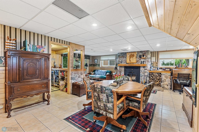 tiled dining space featuring a fireplace and a drop ceiling