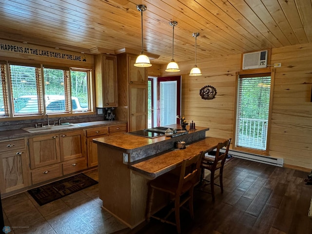 kitchen with hanging light fixtures, black electric stovetop, wooden walls, baseboard heating, and a center island