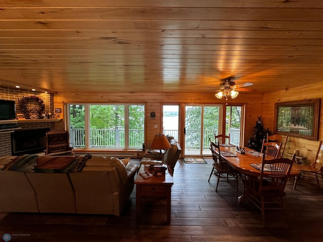 living room featuring wood walls, ceiling fan, wood-type flooring, wood ceiling, and a fireplace