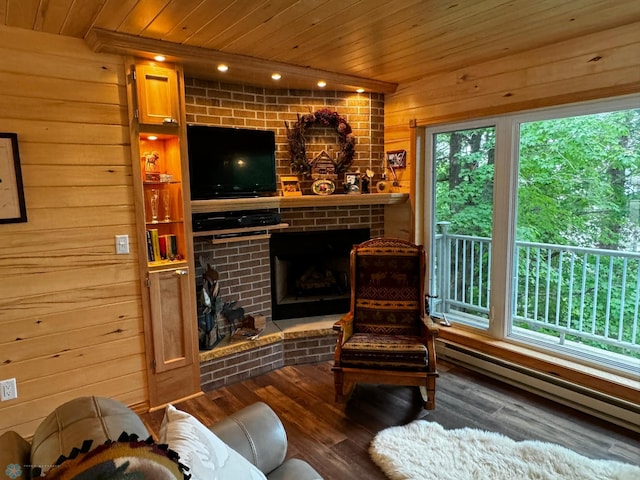 sitting room featuring a brick fireplace, wood-type flooring, wooden ceiling, wood walls, and baseboard heating