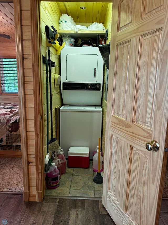 washroom featuring wooden walls, stacked washer / dryer, dark hardwood / wood-style flooring, and wooden ceiling