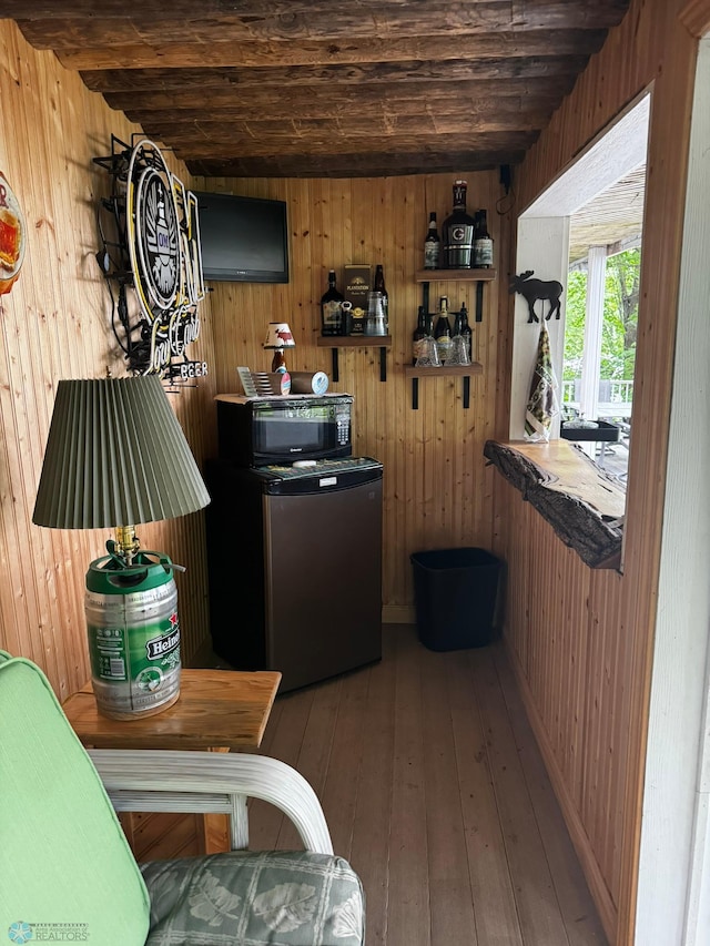 kitchen with wood-type flooring, wooden walls, and refrigerator