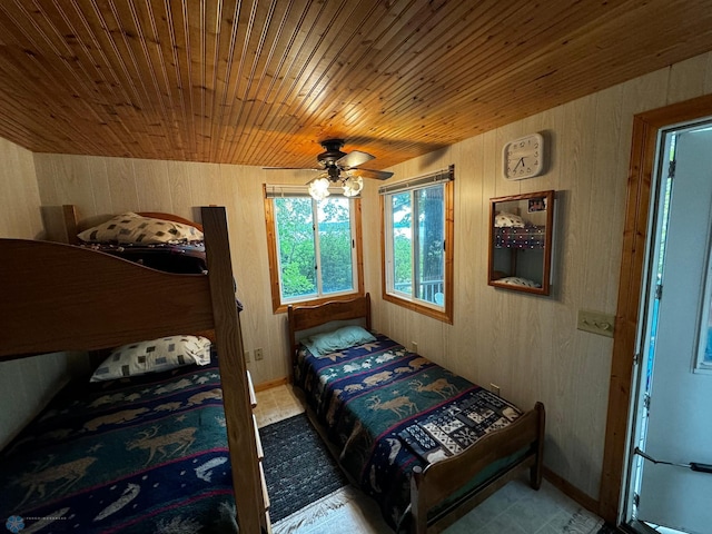 bedroom with wood walls, wooden ceiling, and ceiling fan