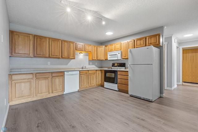 kitchen with light wood-type flooring, white appliances, sink, and a textured ceiling