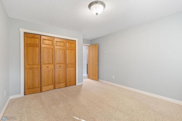 unfurnished bedroom featuring light carpet, a textured ceiling, and a closet