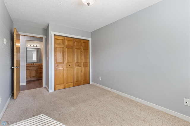 unfurnished bedroom with a closet, carpet floors, sink, and a textured ceiling