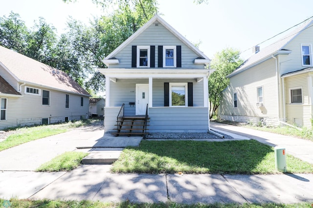 bungalow-style home with covered porch and a front yard