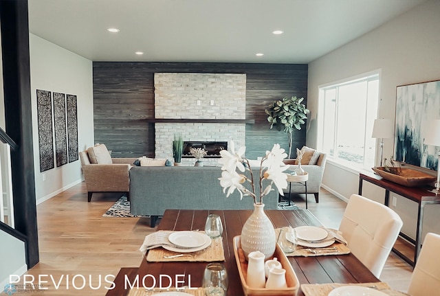 living room with light hardwood / wood-style floors, wooden walls, and a fireplace