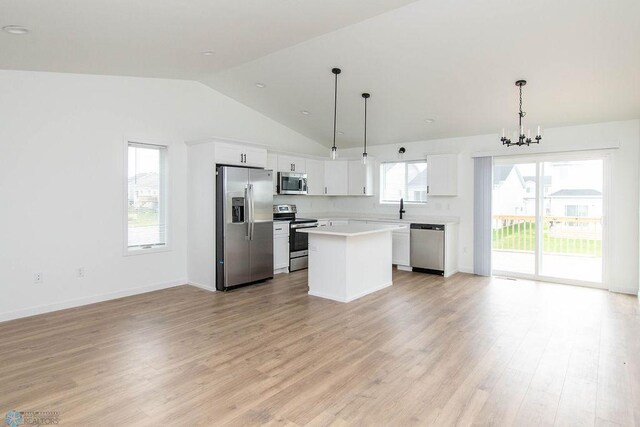 kitchen featuring light hardwood / wood-style flooring, stainless steel appliances, hanging light fixtures, lofted ceiling, and white cabinets