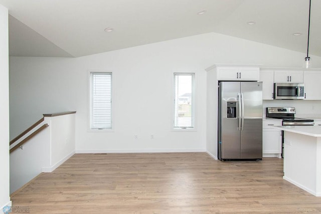 kitchen with lofted ceiling, appliances with stainless steel finishes, light wood-type flooring, and white cabinetry