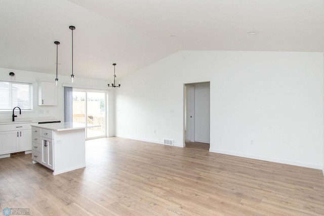 kitchen featuring a kitchen island, vaulted ceiling, light wood-type flooring, and white cabinetry